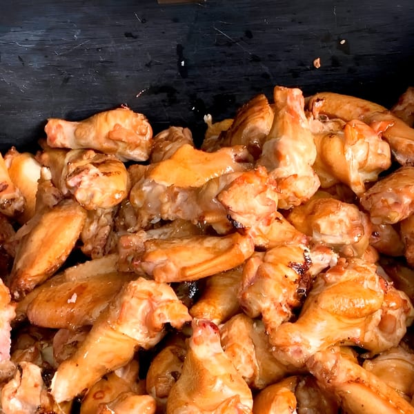 Close-up of a large pile of golden-brown, glistening Chuck's BBQ chicken wings.