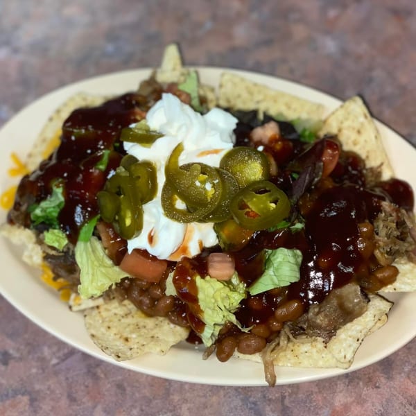Chuck's BBQ nachos with pulled pork, beans, cheese, lettuce, tomatoes, jalapeños, and sour cream.