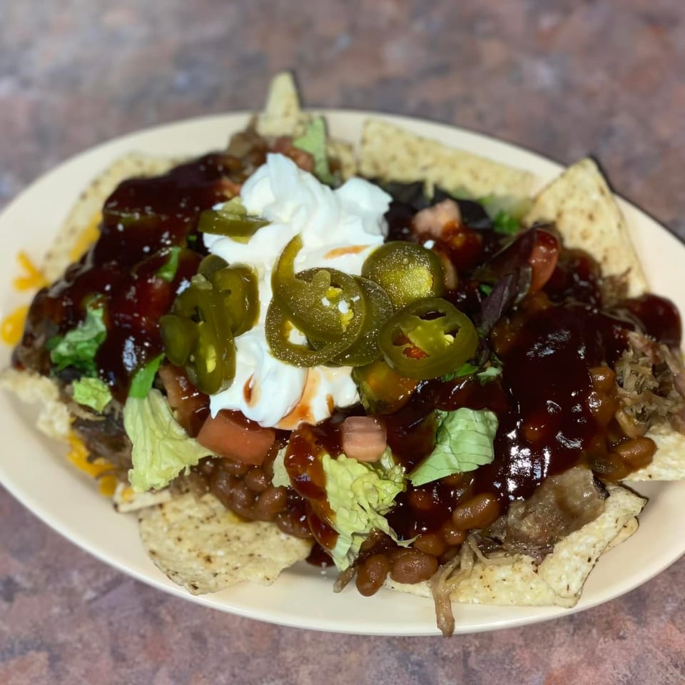 Chuck's BBQ nachos with pulled pork, beans, cheese, lettuce, tomatoes, jalapeños, and sour cream.