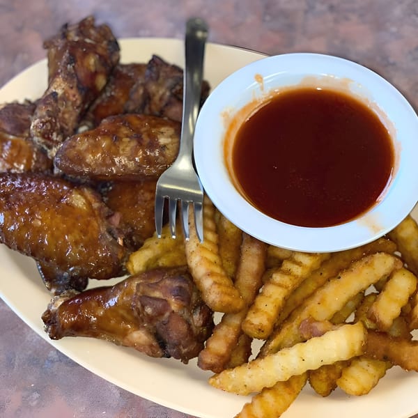 Chuck's BBQ chicken wings and crinkle-cut fries with a side of barbecue sauce.