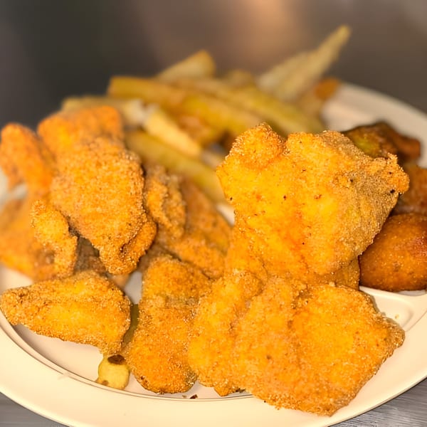 A plate of golden-brown fried catfish fillets and hushpuppies with a side of french fries.